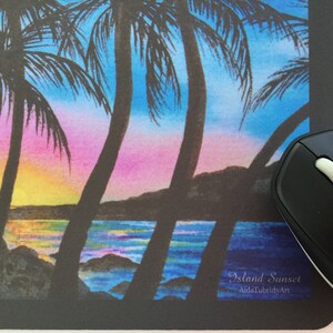 Pode incluir: Tapete de rato com um p&ocirc;r do sol tropical com palmeiras contra um c&eacute;u rosa, azul e amarelo. A assinatura diz "Island Sunset, AidaTubridyArt". Um rato sem fios preto est&aacute; &agrave; direita.