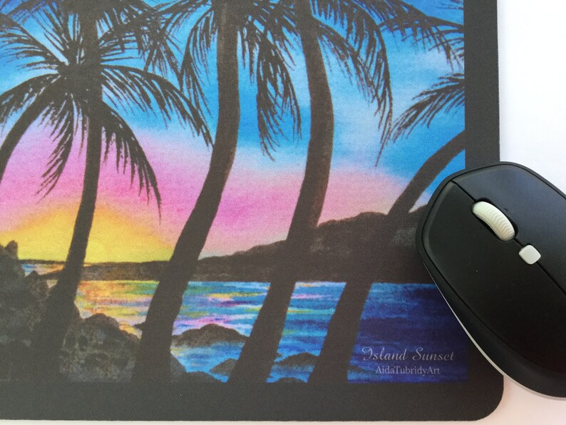 Pode incluir: Tapete de rato com um p&ocirc;r do sol tropical com palmeiras contra um c&eacute;u rosa, azul e amarelo. A assinatura diz "Island Sunset, AidaTubridyArt". Um rato sem fios preto est&aacute; &agrave; direita.