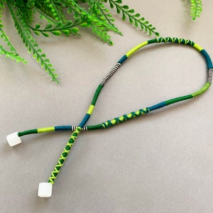 Peut inclure: Un cordon tressé vert, bleu et blanc avec des embouts en plastique blanc. Le cordon est bouclé et prêt à être utilisé comme un cordon ou une dragonne de téléphone.