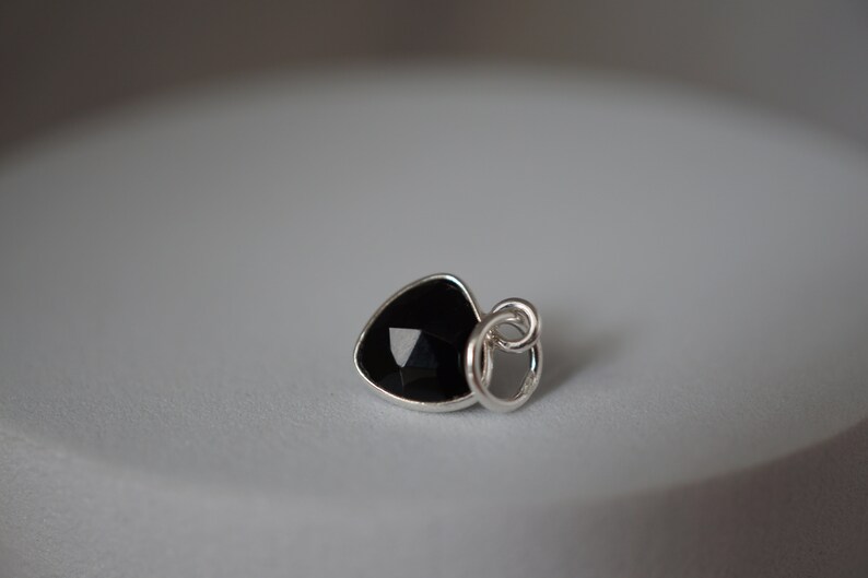 Puede incluir: Un colgante de plata con una piedra preciosa negra en forma de coraz&oacute;n.