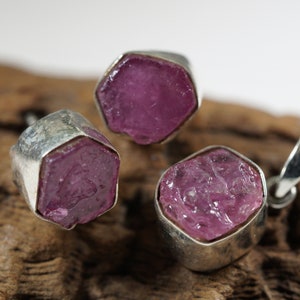 Puede incluir: Tres colgantes de plata con piedras preciosas rosas. Cada colgante presenta una piedra de forma diferente.