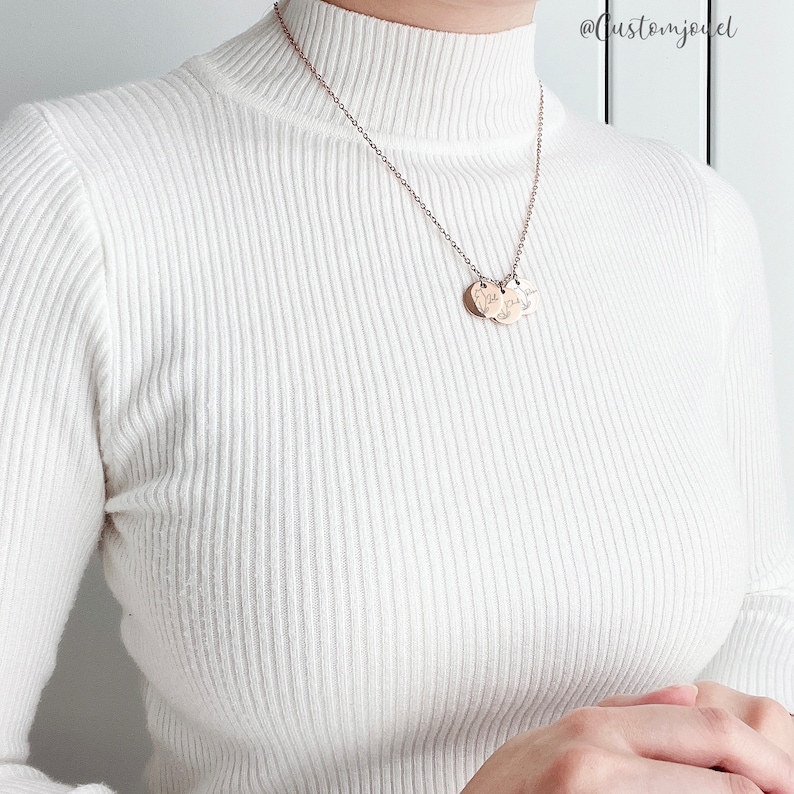 May include: A rose gold-toned necklace featuring a delicate chain and three small, circular, engraved pendants. The necklace is worn over a white, long-sleeved, ribbed mock-neck sweater. The text @customjouel is visible in the upper right corner.