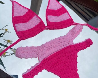 May include: Pink and hot pink striped crochet bikini top and bottom. The top is a triangle style with adjustable straps. The bottom is a high-cut style with a cheeky back.