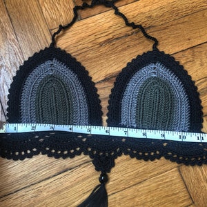 May include: Black, gray, and green crochet bikini top with a tassel. The top measures 10 inches across.