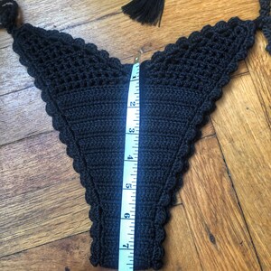 May include: Black crocheted bikini bottom with a scalloped edge, measured with a tape measure to be 7 inches long.