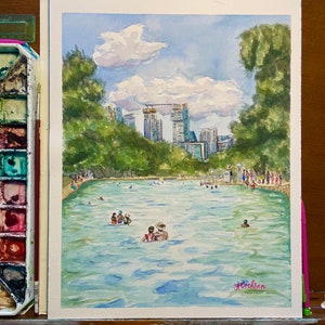 K&ouml;nnte beinhalten: Ein Aquarellgem&auml;lde, das ein &ouml;ffentliches Schwimmbad voller Menschen zeigt, umgeben von &uuml;ppigen gr&uuml;nen B&auml;umen und einer fernen Skyline unter einem blauen Himmel mit wei&szlig;en Wolken. Die Signatur der K&uuml;nstlerin, A. Cochran, ist unten rechts zu sehen.