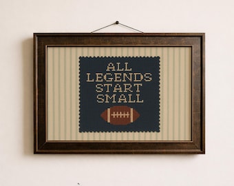 May include: A rectangular wall art piece in a bronzed walnut frame featuring a cross-stitch style print. The design displays the text ALL LEGENDS START SMALL in beige on a dark blue square with a scalloped edge, above a brown football graphic.