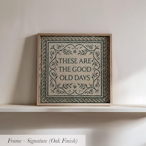May include: Square framed artwork with a mosaic design. The artwork features the text "THESE ARE THE GOOD OLD DAYS" in a decorative font, surrounded by a floral border. The frame has an oak finish.