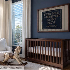 a nursery room with a wooden crib, a rocking horse, and a framed sign on the wall.