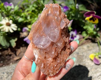 May include: A cluster of pink and brown selenite crystals with a layered, textured appearance. The crystals are translucent and have a natural, earthy look.