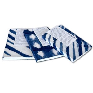 May include: Three rectangular stacks of paper featuring blue and white shibori-style tie-dye patterns. Each stack is topped with a white paper label containing printed text that reads Shibori and additional descriptive information in black ink.