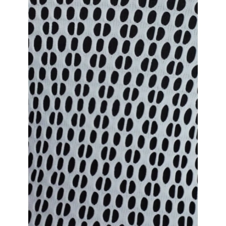 K&ouml;nnte beinhalten: Ein wei&szlig;er Stoff mit einem schwarzen, sich wiederholenden Muster aus ovalen Formen. Die Ovale sind diagonal angeordnet.