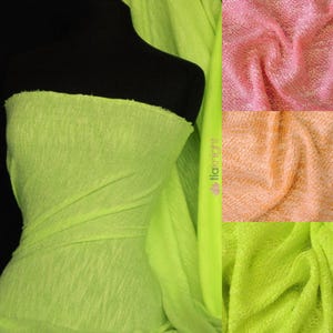 May include: A close-up of a bright green knit fabric. The fabric is soft and textured, with a slightly fuzzy appearance. The fabric is shown in three different folds, with the edges of the fabric visible.
