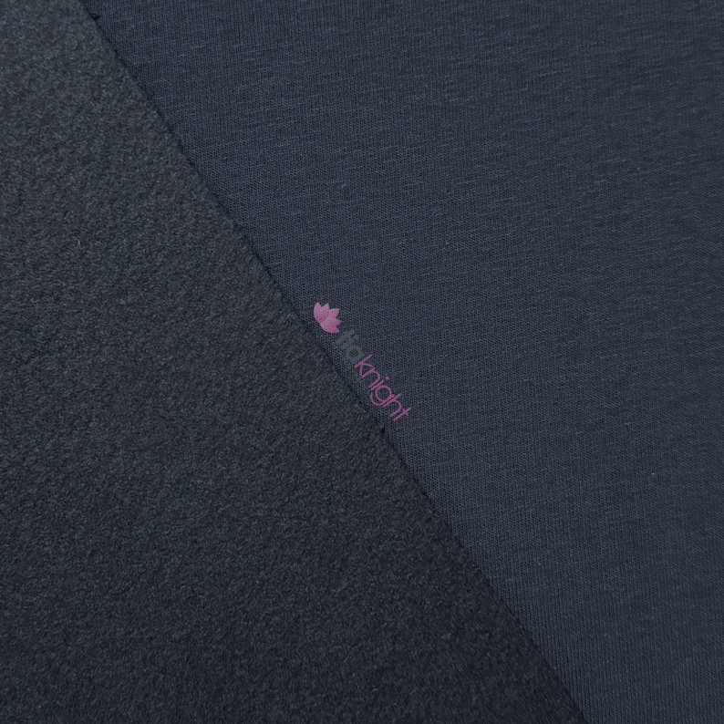 May include: Close-up of two sections of fabric in shades of gray. One section has a textured, fleece-like appearance, while the other is smooth. The brand name "fioknight" is printed in pink on the smooth fabric.
