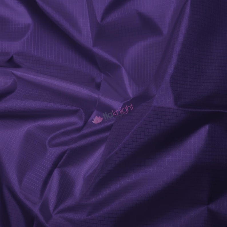 May include: A close-up of a deep purple fabric with a subtle grid pattern. The fabric is draped, creating soft folds and shadows. The texture appears smooth and slightly shiny, suggesting a lightweight material. The logo "liaknight" is visible in the bottom right corner.