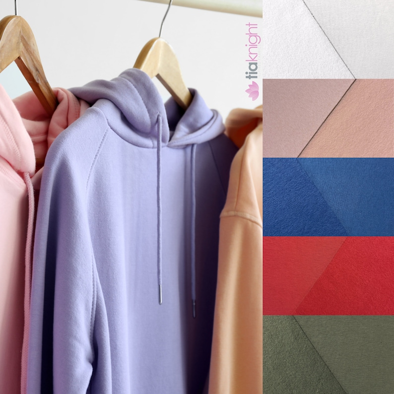 May include: A row of pastel-colored hoodies hanging on wooden hangers. The hoodies are in shades of pink, lavender, and peach. The hoodies have drawstrings and hoods. A color swatch of fabric samples in white, pink, blue, red, and olive green is on the right.