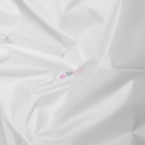 May include: White fabric with a subtle grid pattern, draped and folded, creating soft shadows. The fabric has a slight sheen, and the logo "tiaknight" is visible in the corner.