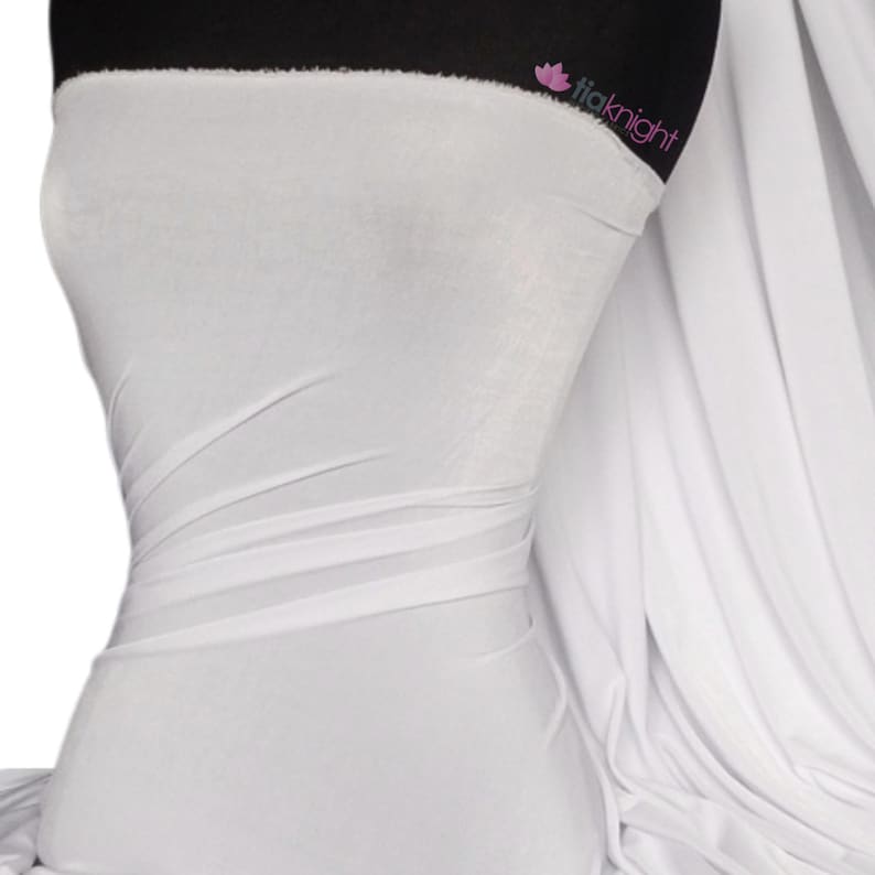 May include: White stretch knit fabric, a smooth and drapey material. The fabric is shown draped over a mannequin.