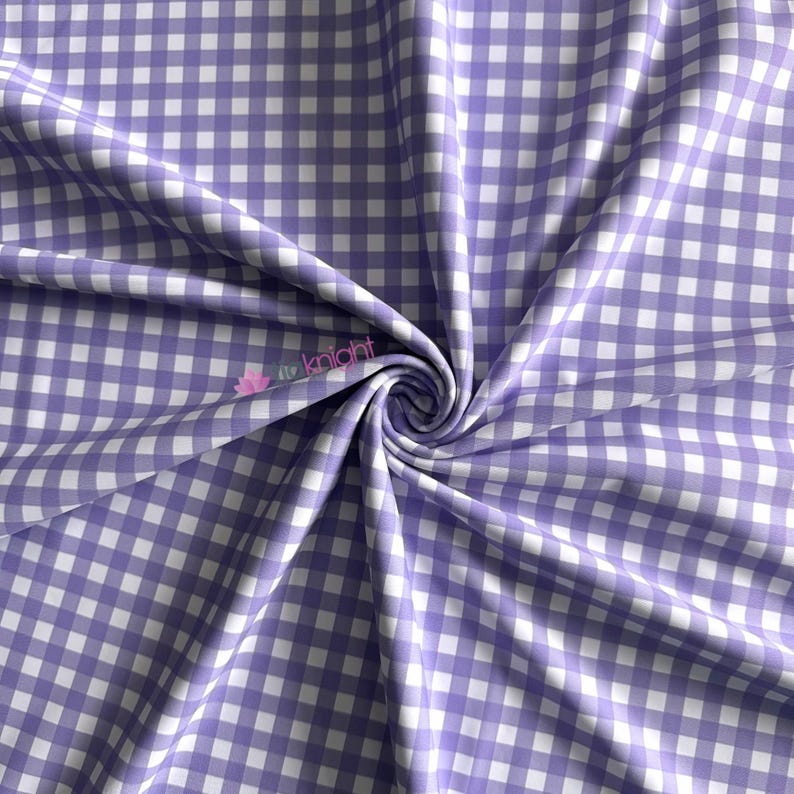 K&ouml;nnte beinhalten: Ein Stoff mit einem klassischen Vichy-Karo-Muster aus abwechselnd hellvioletten und wei&szlig;en Quadraten. Das Material ist zu einem zentralen Wirbel gerafft, wodurch weiche Falten und Drapierungen auf der Oberfl&auml;che entstehen. Der Text "knight" ist in Pink sichtbar.