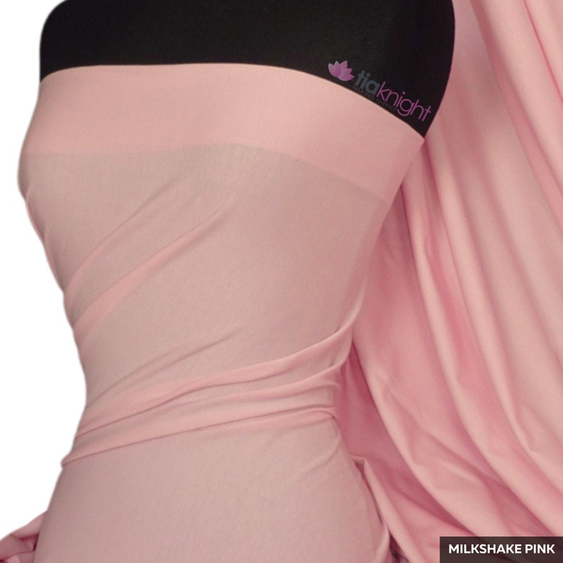 Puede incluir: Una tela rosa claro drapeada sobre un maniqu&iacute;. La tela es suave y fluida, con las palabras "Milkshake Pink" en un recuadro blanco en la parte inferior derecha. La marca "tiaknight" es visible en la esquina superior derecha.