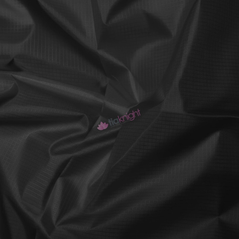 May include: Close-up of black fabric with a subtle grid pattern. The material is draped, creating folds and shadows that add depth. The fabric has a slight sheen, suggesting a smooth texture. The logo "tiaknight" is visible in the corner.