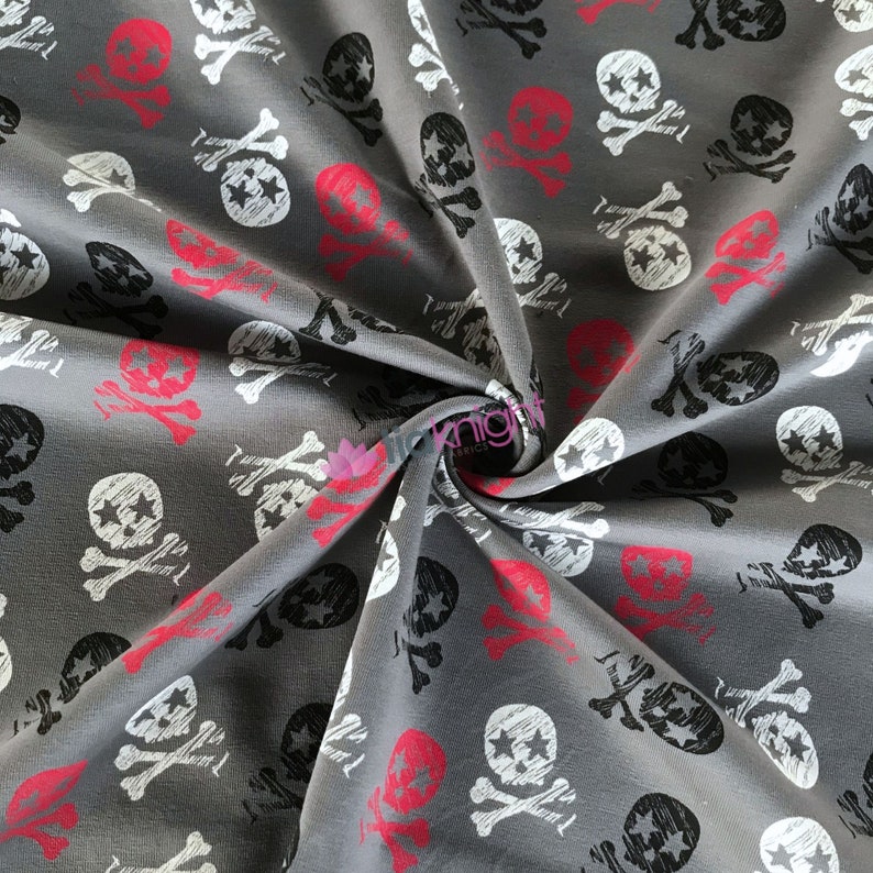 May include: Gray fabric with a repeating pattern of white and black skull and crossbones with a red star in the center of each skull.