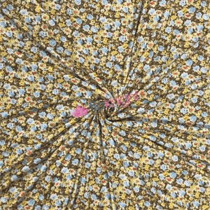 May include: A brown fabric with a small floral print in shades of yellow, blue, and red.