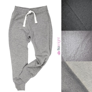 Pode incluir: Calças de moletom cinzas com cordão branco. As calças de moletom têm um caimento relaxado e uma bainha com punhos.