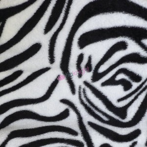 May include: Black and white zebra print fabric with a soft, fuzzy texture.