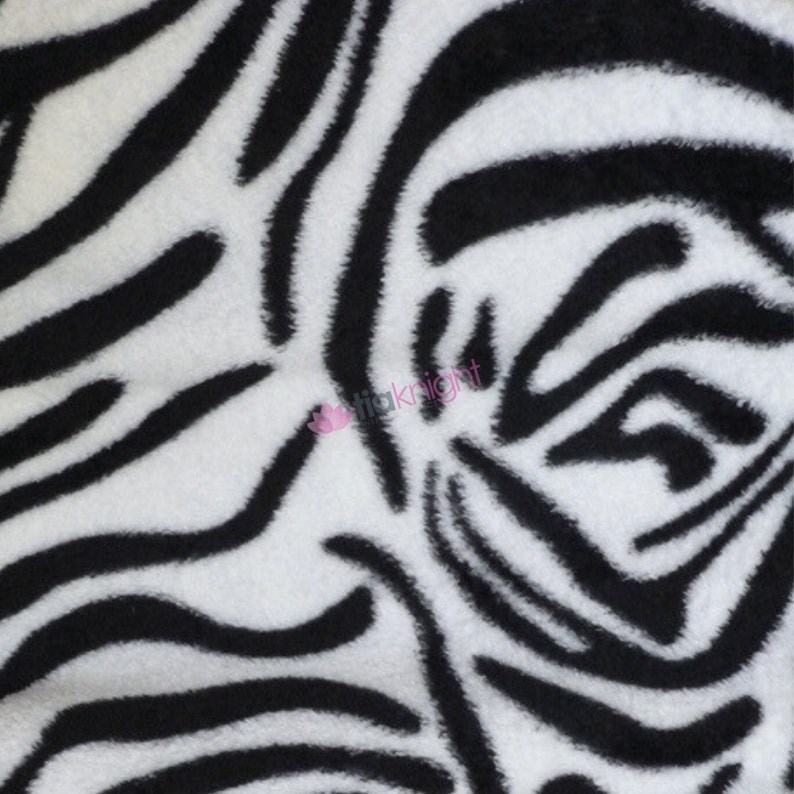 May include: Black and white zebra print fabric with a soft, fuzzy texture.