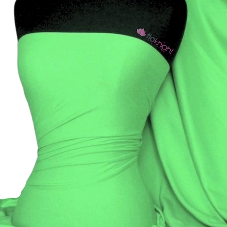 Puede incluir: Una tela verde brillante con una textura suave. La tela est&aacute; drapeada sobre un maniqu&iacute; y tiene un ligero brillo.