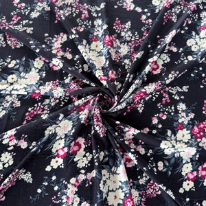 May include: Black fabric with a white and pink floral print. The fabric is soft and has a subtle sheen.