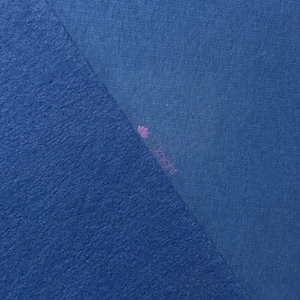 May include: Two samples of blue fabric are displayed. One section has a textured, fuzzy surface, while the other is smooth. The fabrics are a similar shade of blue, with a slight difference in texture. The image is well-lit, showing the details of the materials.