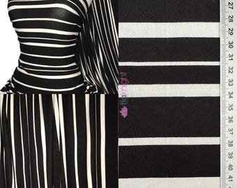 May include: Black and white striped fabric displayed on a mannequin and in a flat lay. The fabric has thick, horizontal white stripes against a black background. A ruler with centimeter markings is visible on the right side of the image.