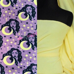 May include: Purple fleece fabric with a repeating pattern of a woman's face with a crescent moon and stars. The fabric is shown next to a solid yellow fleece fabric.