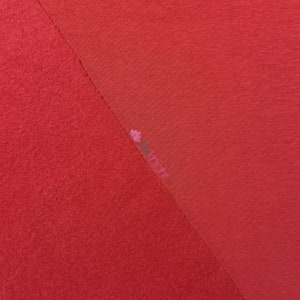 May include: A diagonal split image showcasing two distinct red fabric textures. One side features a plush, textured material, while the other displays a smooth, woven fabric. The image is well-lit, highlighting the contrast between the textures.