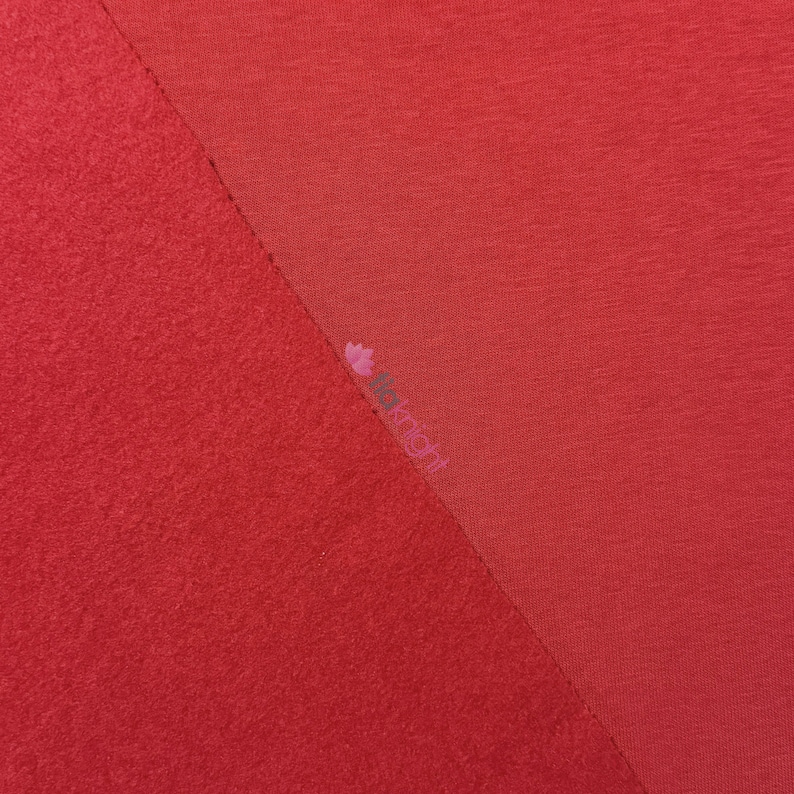 May include: A diagonal split image showcasing two distinct red fabric textures. One side features a plush, textured material, while the other displays a smooth, woven fabric. The image is well-lit, highlighting the contrast between the textures.