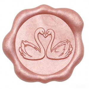 May include: A rose gold wax seal with a scalloped edge. The seal features two swans facing each other, their necks forming a heart shape. The wax has a subtle shimmer, and the design is centered on the seal.