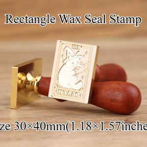 Op de afbeelding: Een goudkleurige rechthoekige zegelstempel met een houten handvat. De stempel toont een kat met een heksenhoed en een toverstaf. De stempel meet 30 x 40mm. De tekst "Rectangle Wax Seal Stamp" staat boven de stempel.