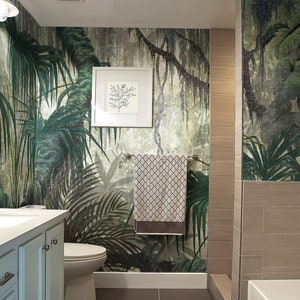 Puede incluir: Un ba&ntilde;o con un papel tapiz de jungla tropical con exuberantes hojas verdes de palmeras y enredaderas. El ba&ntilde;o tiene un lavabo de porcelana blanca, un inodoro blanco y una ba&ntilde;era blanca.