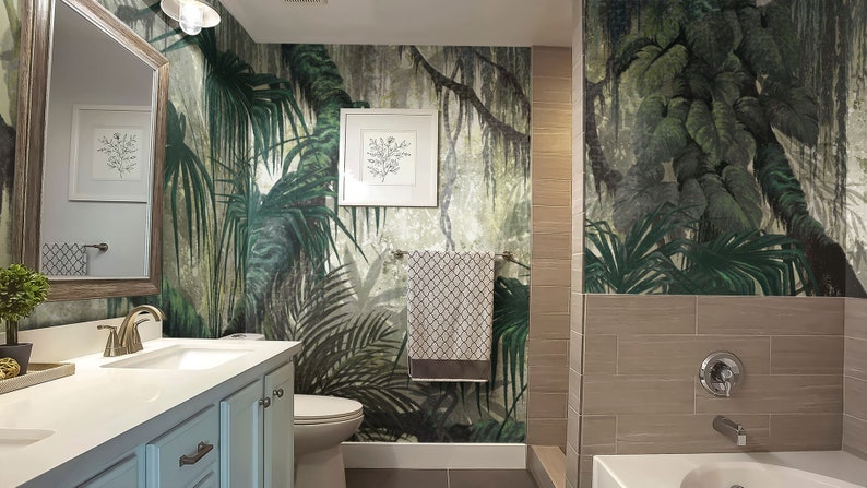 Puede incluir: Un ba&ntilde;o con un papel tapiz de jungla tropical con exuberantes hojas verdes de palmeras y enredaderas. El ba&ntilde;o tiene un lavabo de porcelana blanca, un inodoro blanco y una ba&ntilde;era blanca.