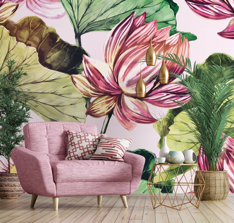 Pu&ograve; includere: Una poltrona rosa con gambe in legno e due cuscini decorativi &egrave; posta di fronte a una carta da parati floreale con grandi fiori rosa e verdi. Un tavolino dorato e lampade a sospensione completano l'arredamento.