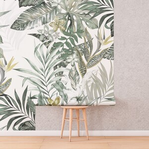 May include: A white background with a green and gold tropical leaf wallpaper design. The wallpaper is partially rolled up, revealing a wooden stool.