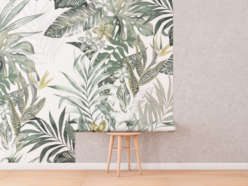 May include: A white background with a green and gold tropical leaf wallpaper design. The wallpaper is partially rolled up, revealing a wooden stool.