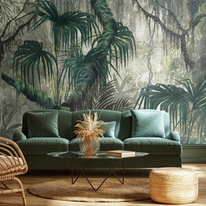 Puede incluir: Un sof&aacute; de terciopelo verde con un fondo de papel tapiz con estampado de jungla tropical. El sof&aacute; tiene un marco de madera y una mesa de caf&eacute; de madera clara con una tapa de vidrio. Tambi&eacute;n hay una silla de mimbre y un reposapi&eacute;s de mimbre en la habitaci&oacute;n.