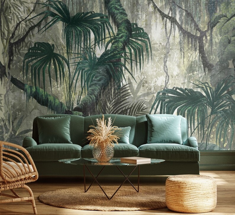 Puede incluir: Un sof&aacute; de terciopelo verde con un fondo de papel tapiz con estampado de jungla tropical. El sof&aacute; tiene un marco de madera y una mesa de caf&eacute; de madera clara con una tapa de vidrio. Tambi&eacute;n hay una silla de mimbre y un reposapi&eacute;s de mimbre en la habitaci&oacute;n.