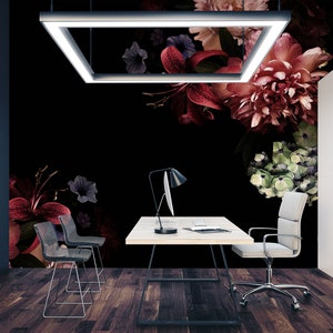 May include: A modern office space with a black wall featuring a floral mural. The mural features red, pink, and green flowers on a black background. A white desk with a black chair and a lamp sits in front of the mural.