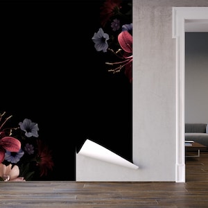 May include: A black and white floral wallpaper with a peel-and-stick application. The wallpaper features a dark background with pink, red, and blue flowers. The wallpaper is being applied to a wall in a room with a doorway leading to another room.
