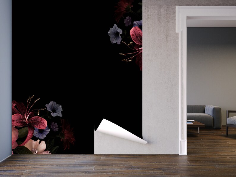 May include: A black and white floral wallpaper with a peel-and-stick application. The wallpaper features a dark background with pink, red, and blue flowers. The wallpaper is being applied to a wall in a room with a doorway leading to another room.