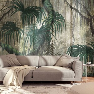Puede incluir: Un sof&aacute; gris con una manta blanca delante de un mural de pared que representa una exuberante escena de jungla verde con palmeras y enredaderas.